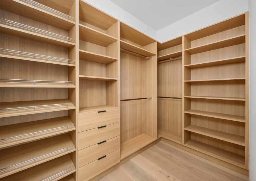 Modern walk-in closet with wooden shelves.
