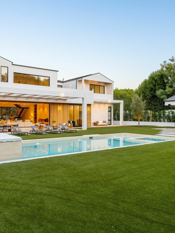 Modern luxury home with pool and spacious backyard. A mid-century modern living room with designer furniture, an indoor garden with a fountain, and a large window revealing a forest landscape at sunset.